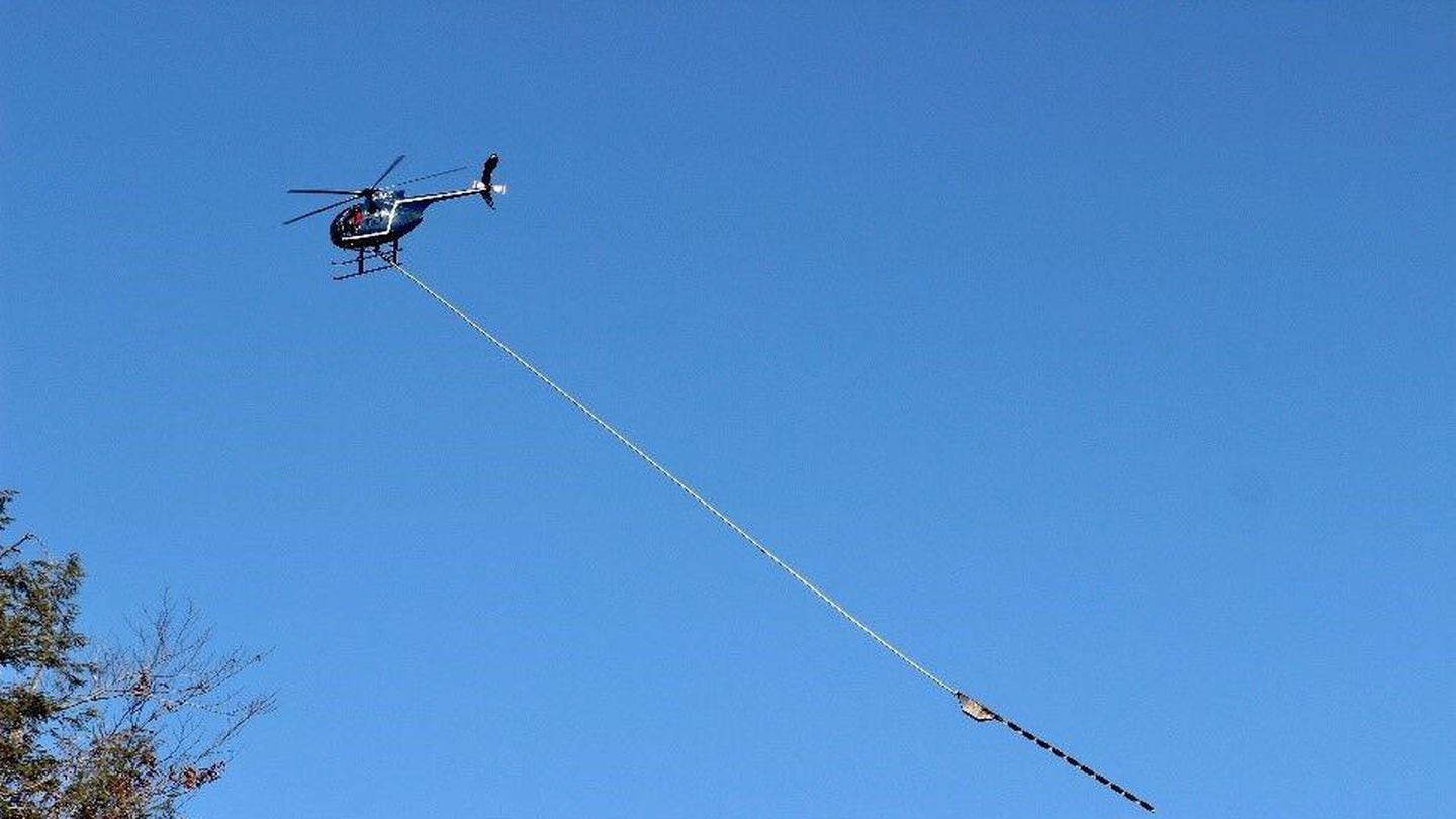 A 10-bladed saw dangled below a Hughes 369D helicopter in a campaign by Eversource to trim trees near its transmission lines.