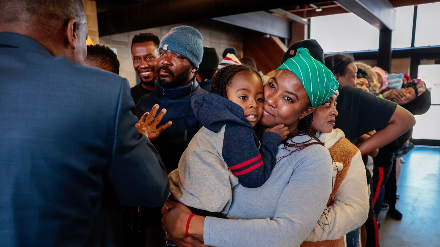 Mireille Pierre comforted her son Marventz, 3, while Dieufort Fleurissaint, aka "Pastor Keke," spoke to a group of Haitian migrants at the state's emergency overflow shelter for migrants at the Melnea A. Cass Recreational Complex in Boston. Pastor Keke was helping distribute donations with Pastor Miniard Culpepper of Pleasant Hill Missionary Baptist Church.